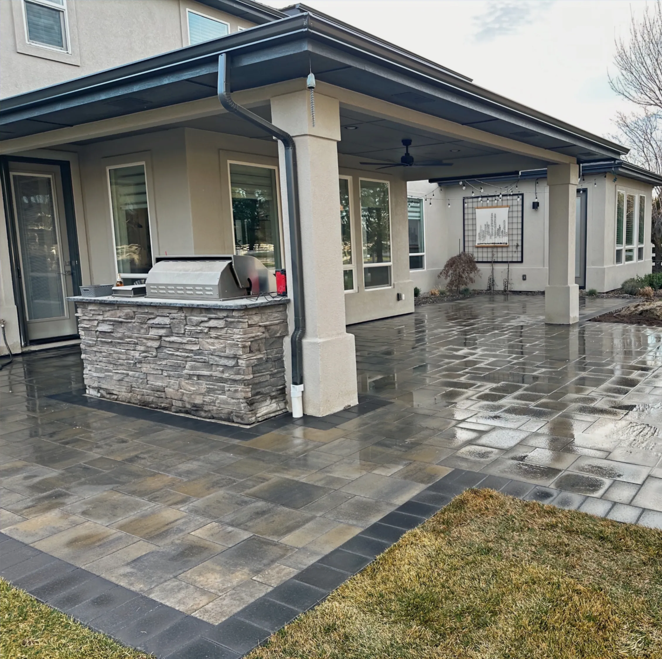 Belgard paver patio with a charcoal border wrapping a covered patio and stacked-stone BBQ island in Eagle, Idaho