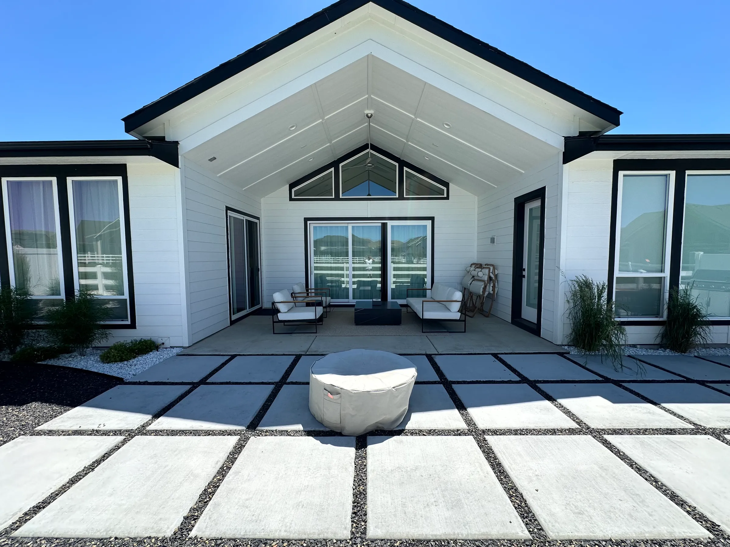Modern concrete pads with gravel joints leading to a covered patio, with a covered precast fire pit