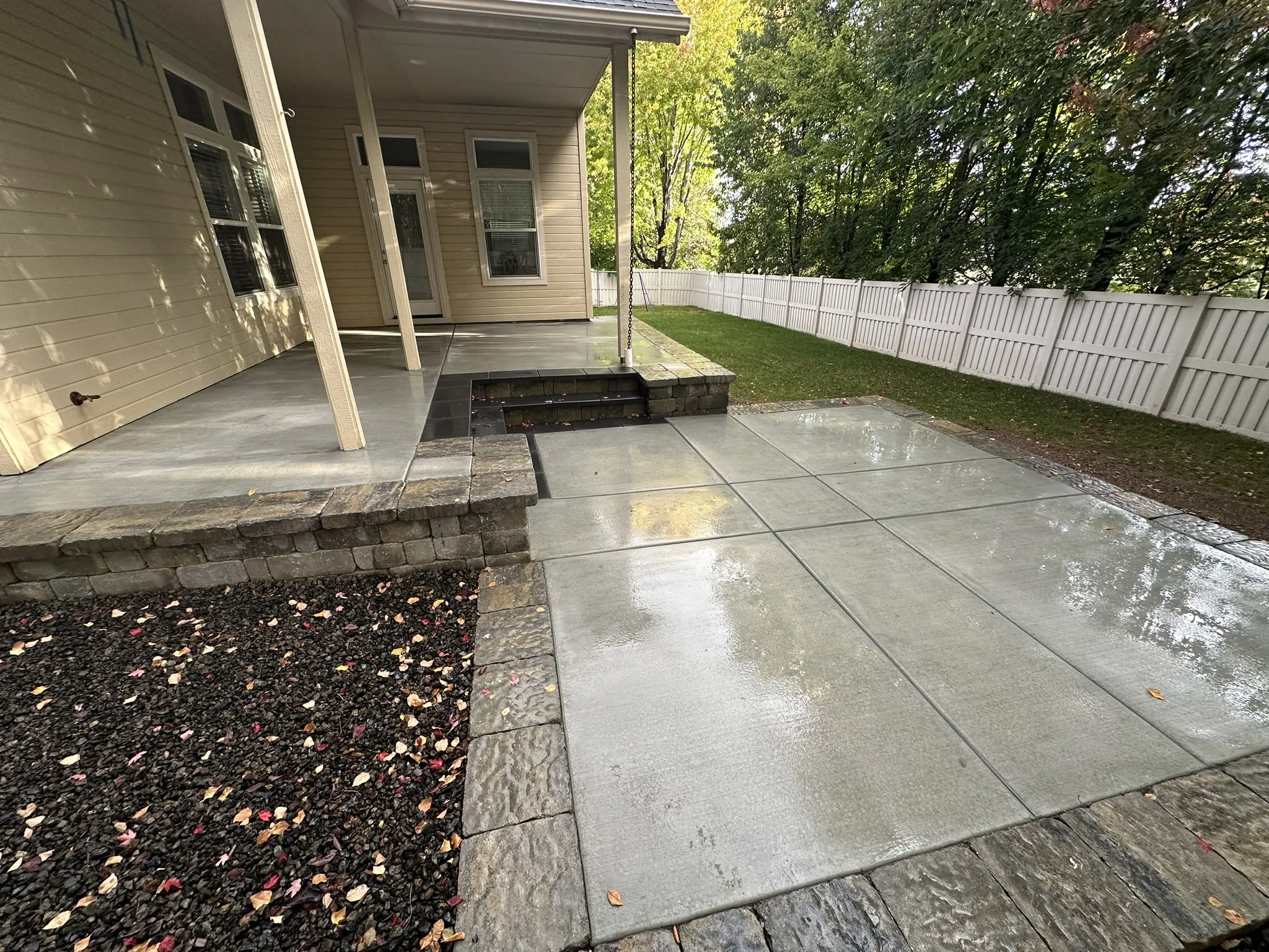 Freshly poured concrete patio with precise control joints and a raised seat-wall step