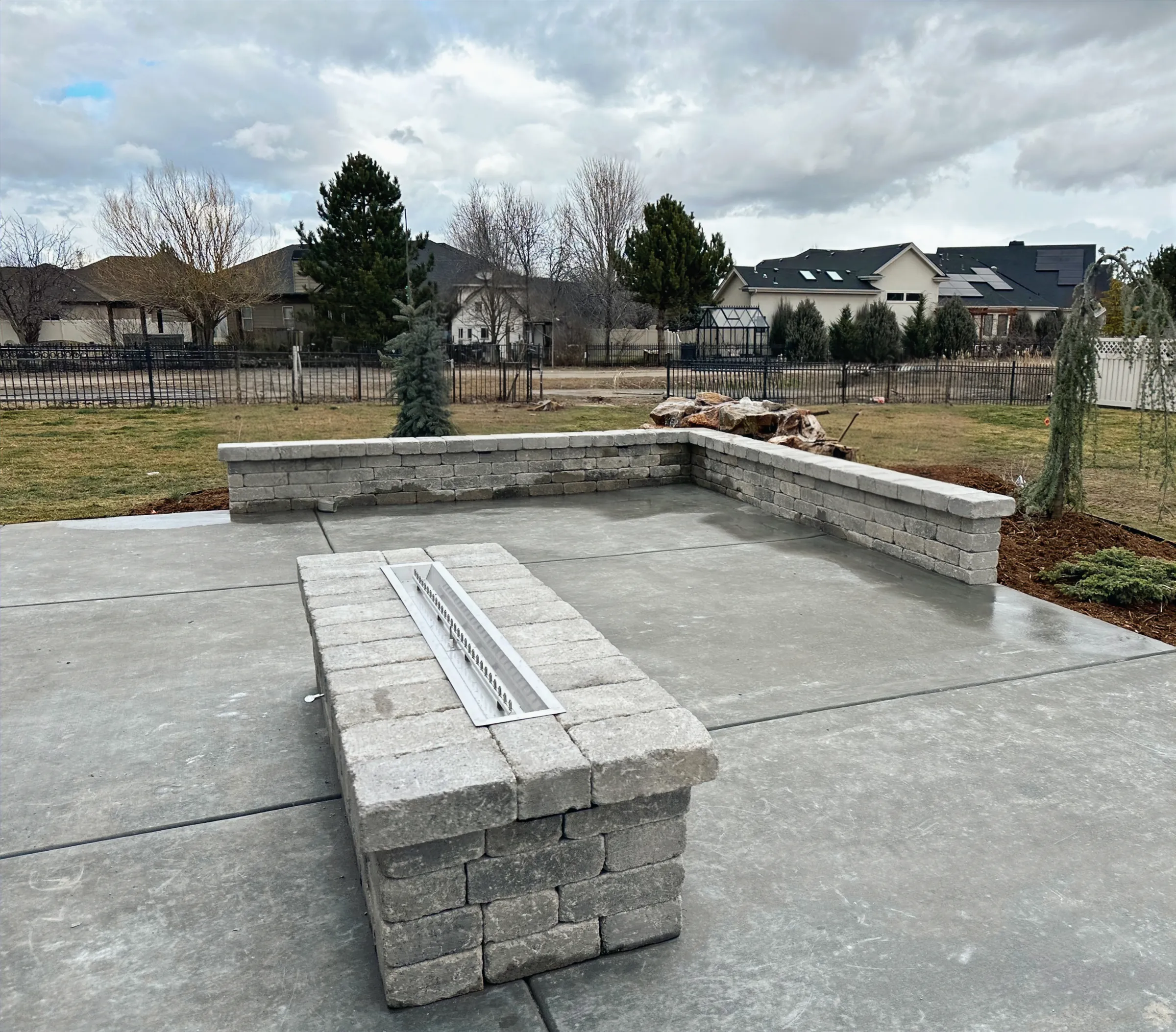 Concrete patio in Eagle, Idaho with a linear gas fire pit and a block seat wall