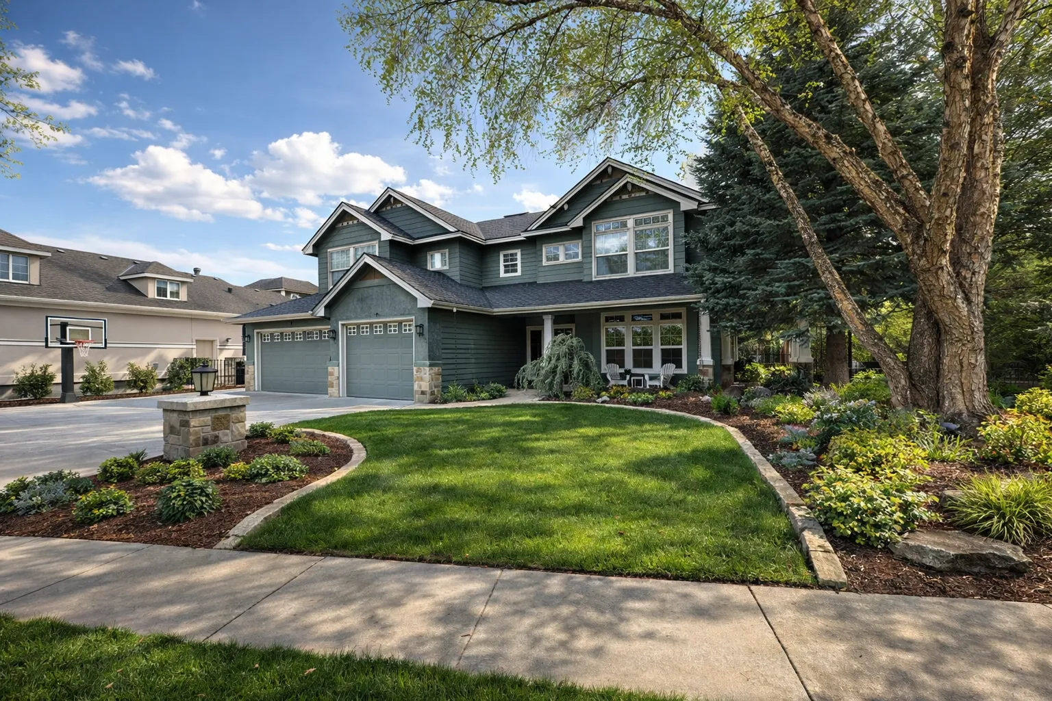 Front yard landscape in Eagle, Idaho with curved lawn, layered planting beds and mature trees