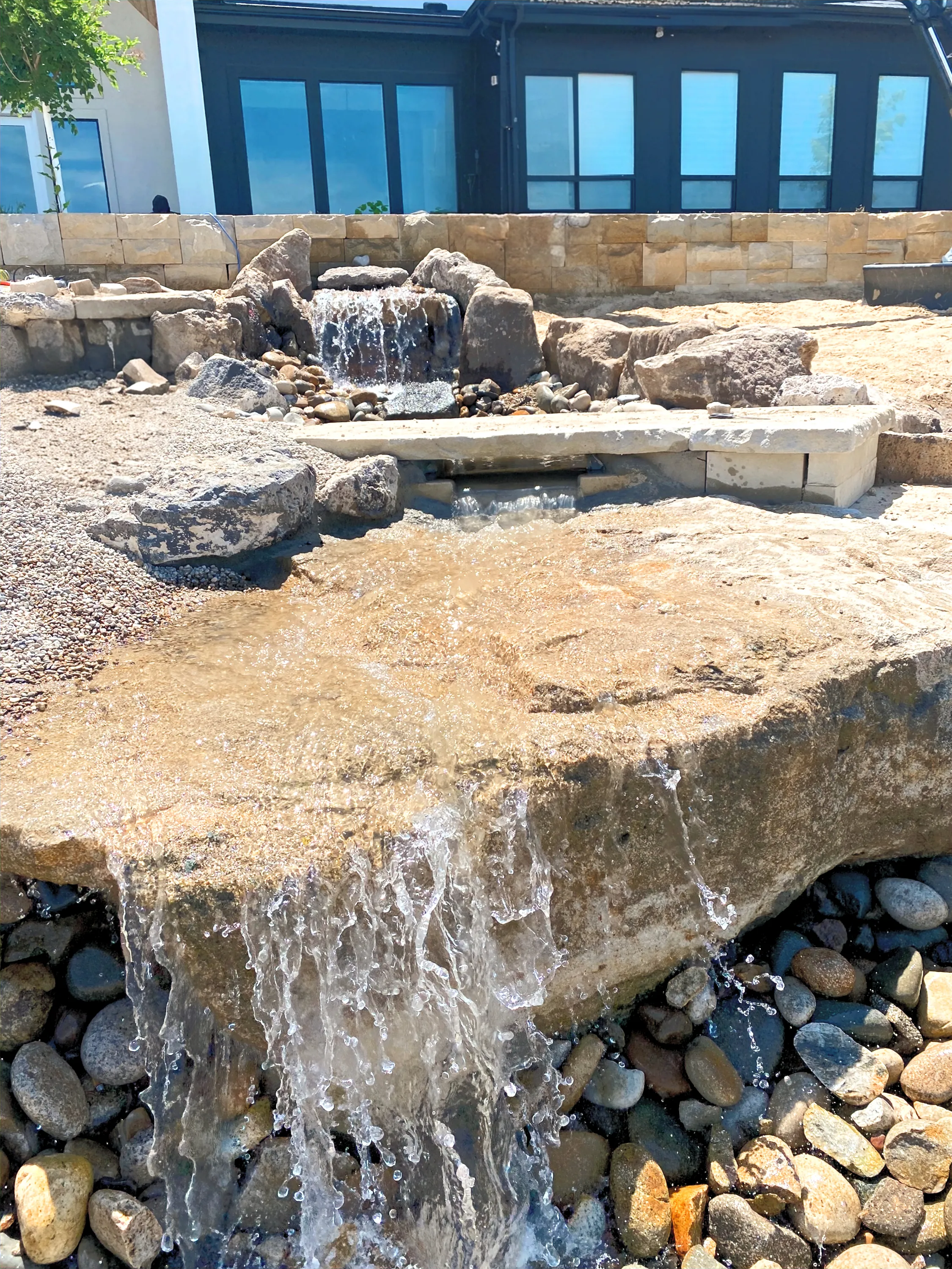 Water spilling over a natural stone slab into a rock-lined basin