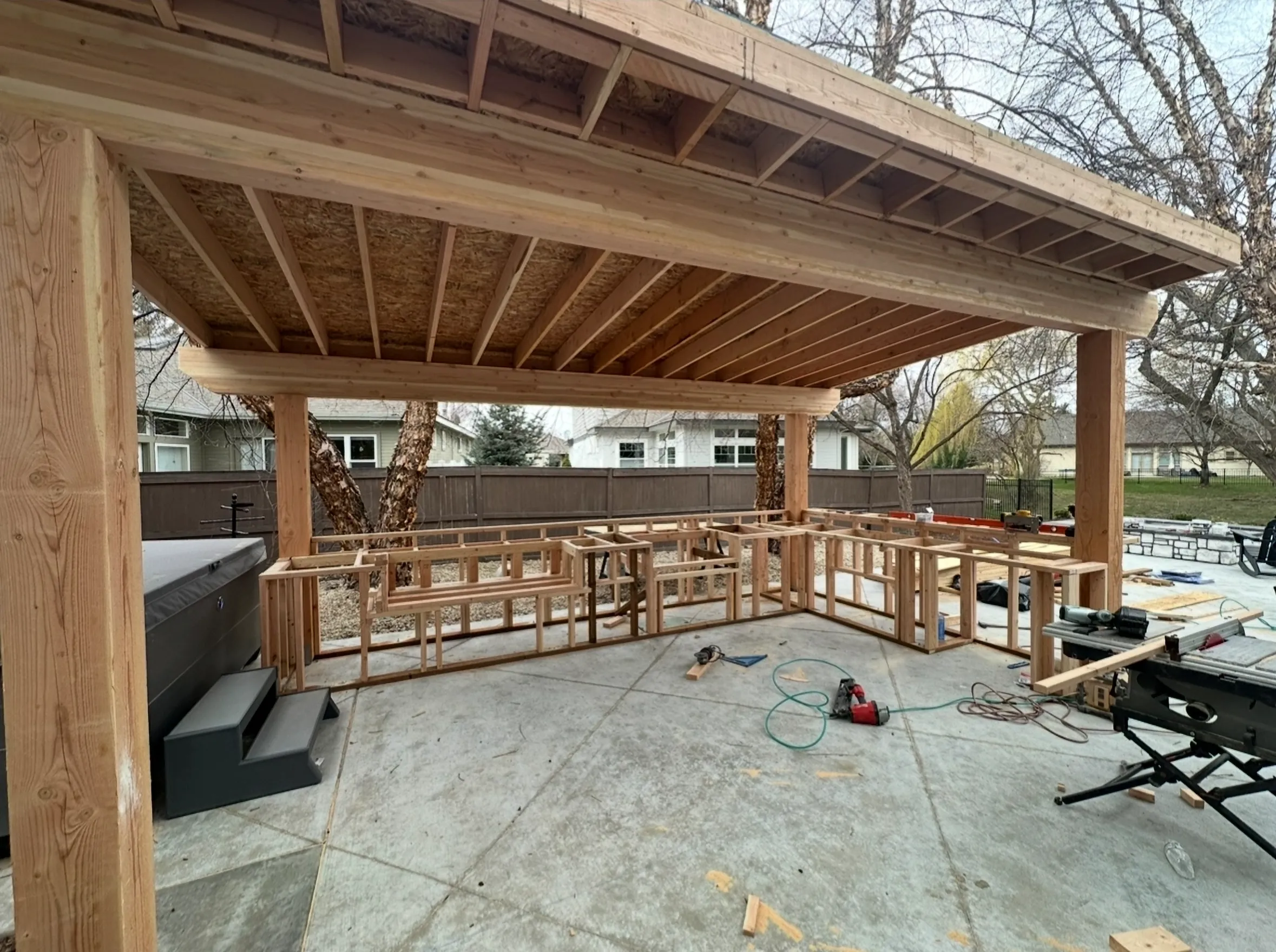 Framing in progress for a standalone outdoor kitchen structure on a new concrete patio