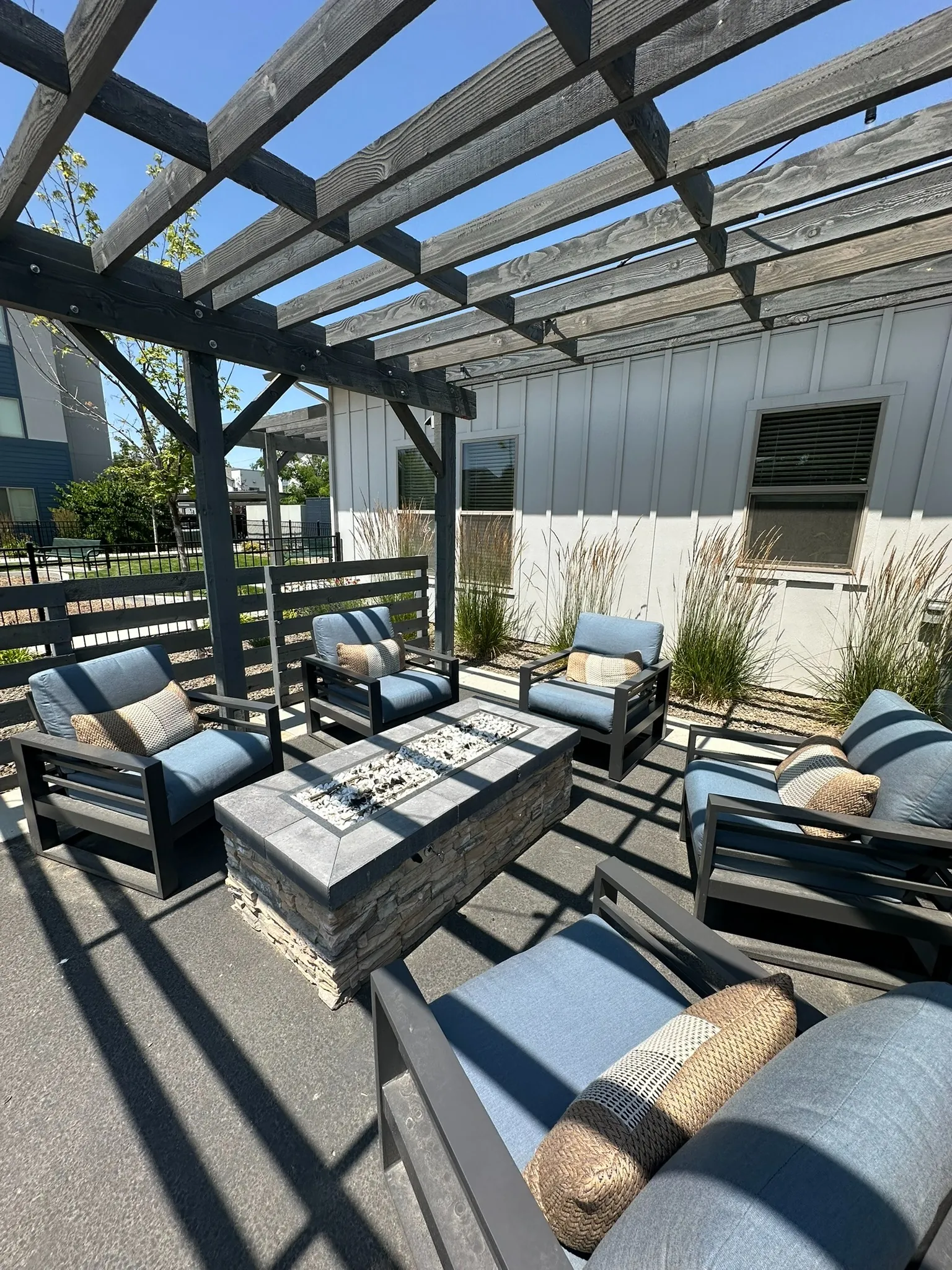 Pergola lounge with deep-seated sofas around a stone fire table