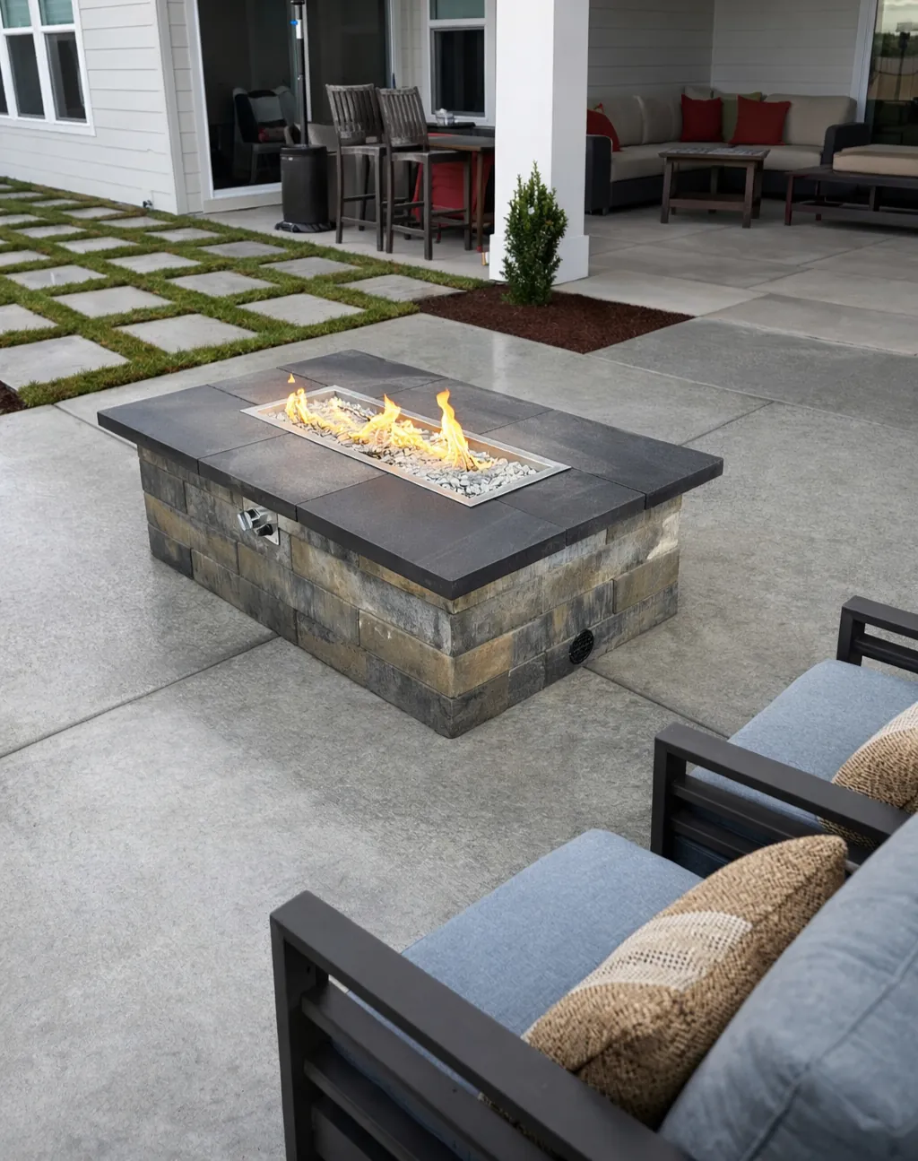 Stacked-block gas fire table with a precision capstone on a concrete patio