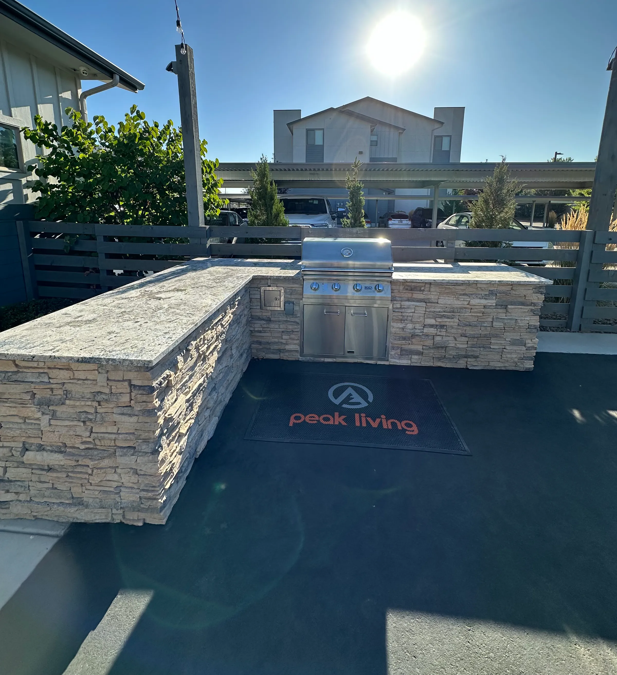 L-shaped stacked-stone BBQ island with a built-in stainless grill on a community patio