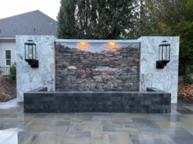 Stacked stone water wall framed by stone panels and lanterns